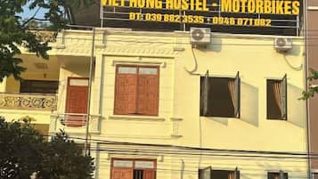 A building with a sign for 'VIET HUNG HOSTEL - MOTORBIKES' and contact numbers.