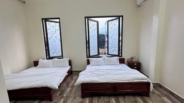 A room with two beds, a wooden floor, and large windows with frosted glass. - VietHung Hostel-Motorbikes Renta-Tuor (Ha Giang)