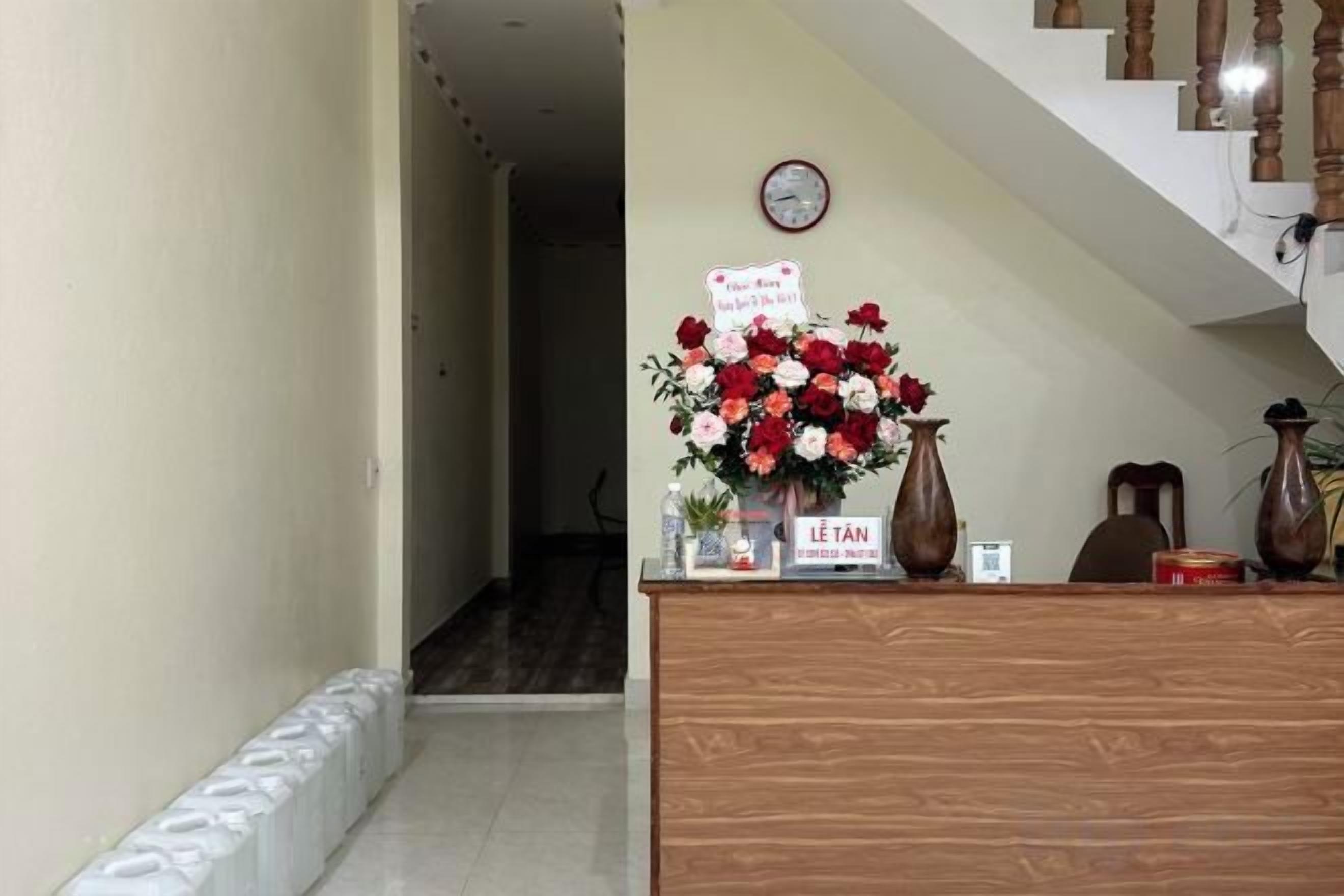 A reception desk with a floral arrangement, a clock, and a sign indicating a 'Welcome Back' message.