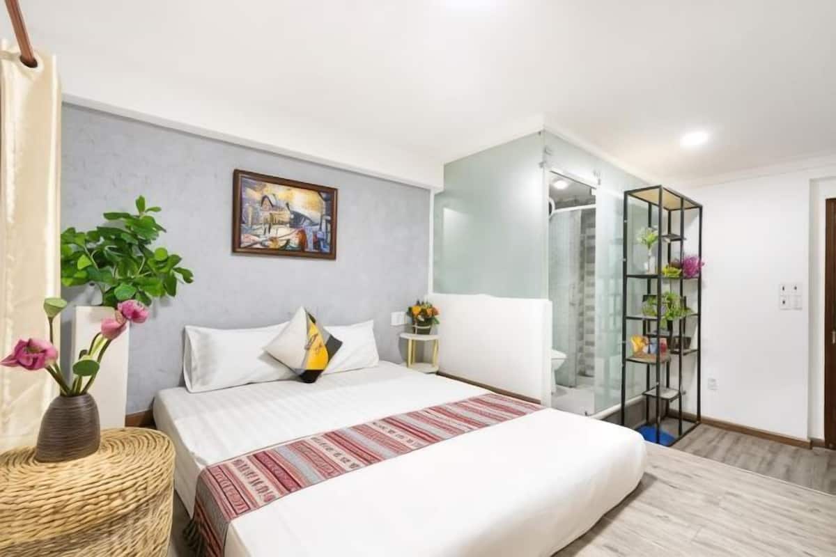 Une chambre d’hôtel moderne avec un grand lit, une douche à parois de verre, une étagère décorative et un tableau.