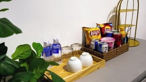 Een dienblad met snacks, drankjes en een kleine plant op een tafel.