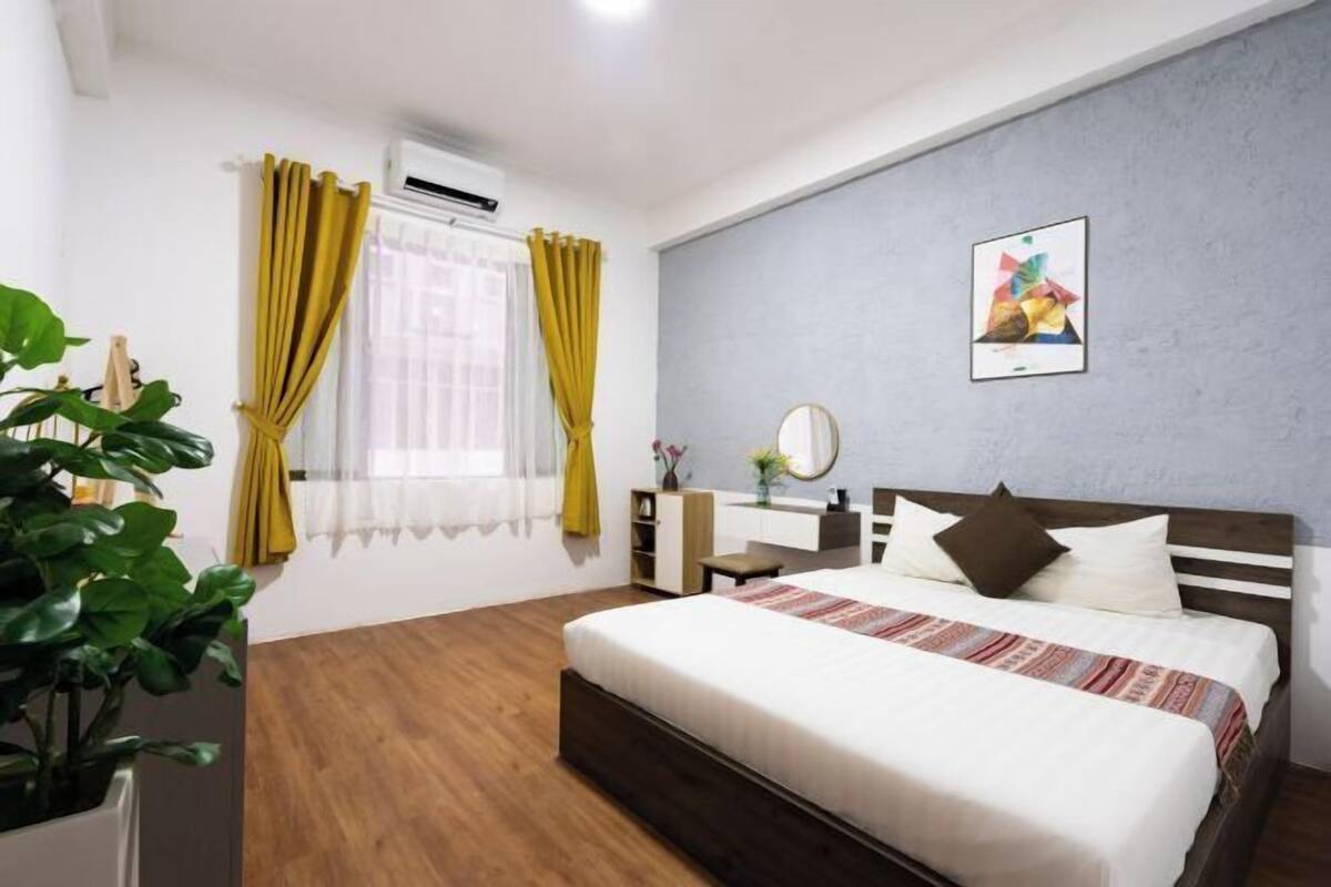 Une chambre à coucher avec un lit, une table de chevet, un miroir et une plante en pot.