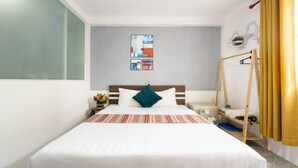 Hotelkamer met een bed, nachtkastje, wanddecoratie, hanglamp en raam met gordijnen.