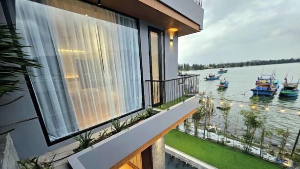 A modern building with a balcony overlooking a body of water with boats. - Villa SuSu (Da Nang)