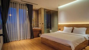 A modern bedroom with a wooden bed, a nightstand, and a glass shower enclosure. - Villa SuSu (Da Nang)