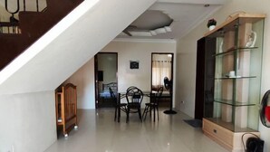 A spacious living area with a staircase, a dining table with chairs, and a glass cabinet with decorative items. - Bluewaves Resort Moalboal by Hiverooms (Moalboal)