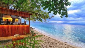 Eine Strandbar mit Holzkonstruktion, einem Stuhl und Blick auf das Meer.