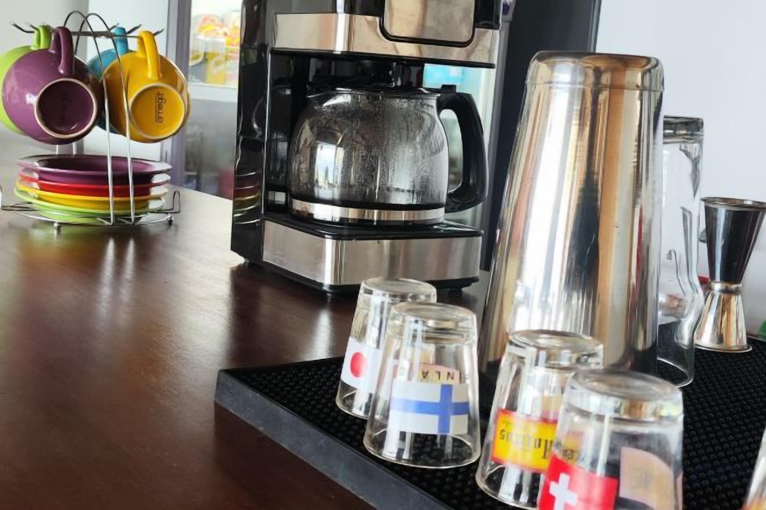 A kitchen area with a coffee maker, a kettle, and several glass containers with flags.
