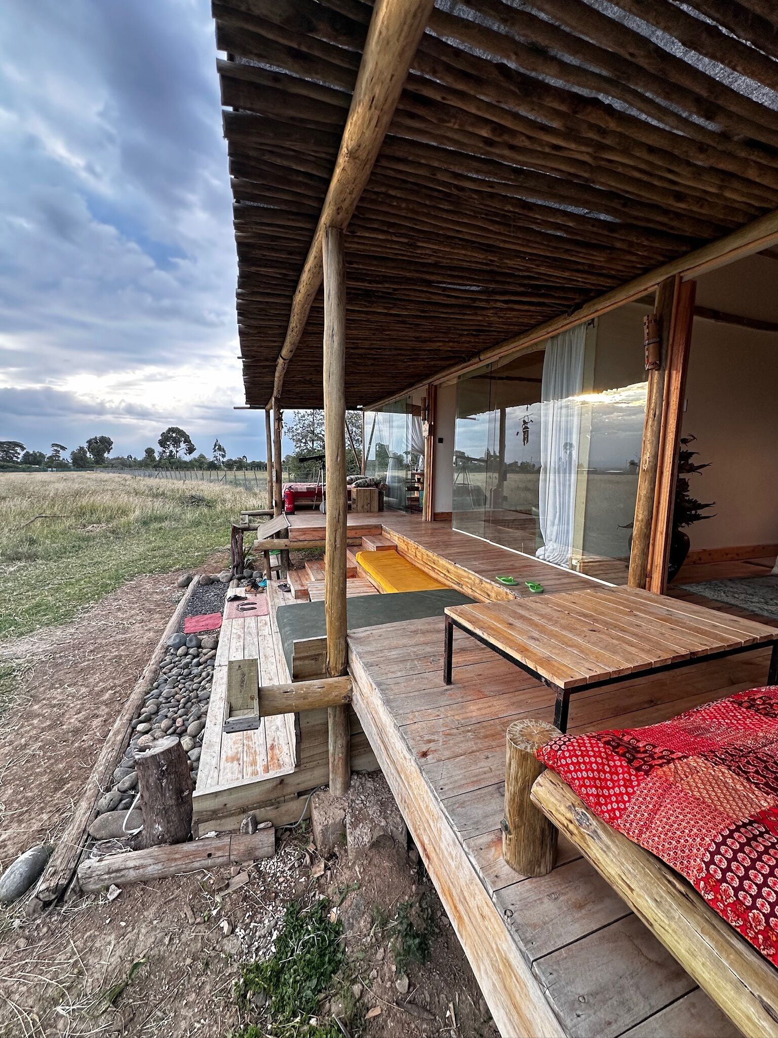 An outdoor wooden deck with a covered seating area, a table, and a bench.
