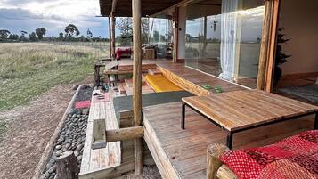 An outdoor wooden deck with a covered seating area, a table, and a bench.