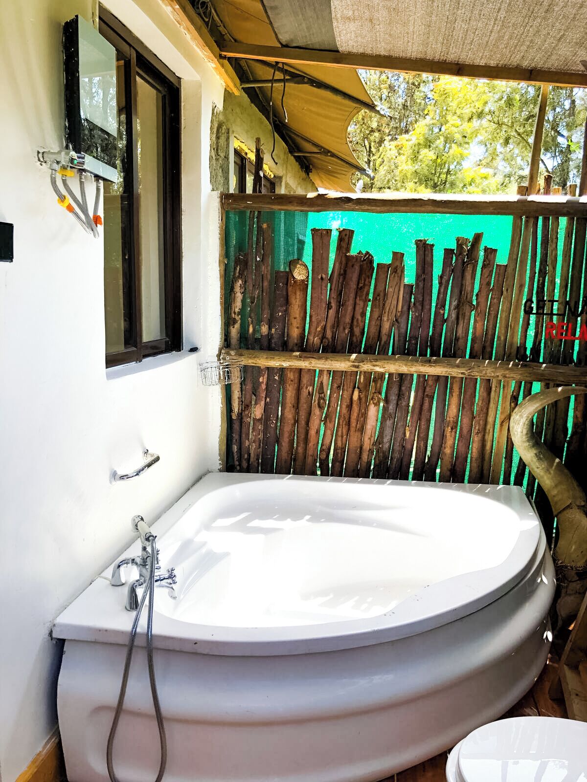 A bathroom with a large bathtub, a window, and a wooden fence.