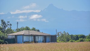 A single-story building with a corrugated metal roof, surrounded by a grassy field and trees.