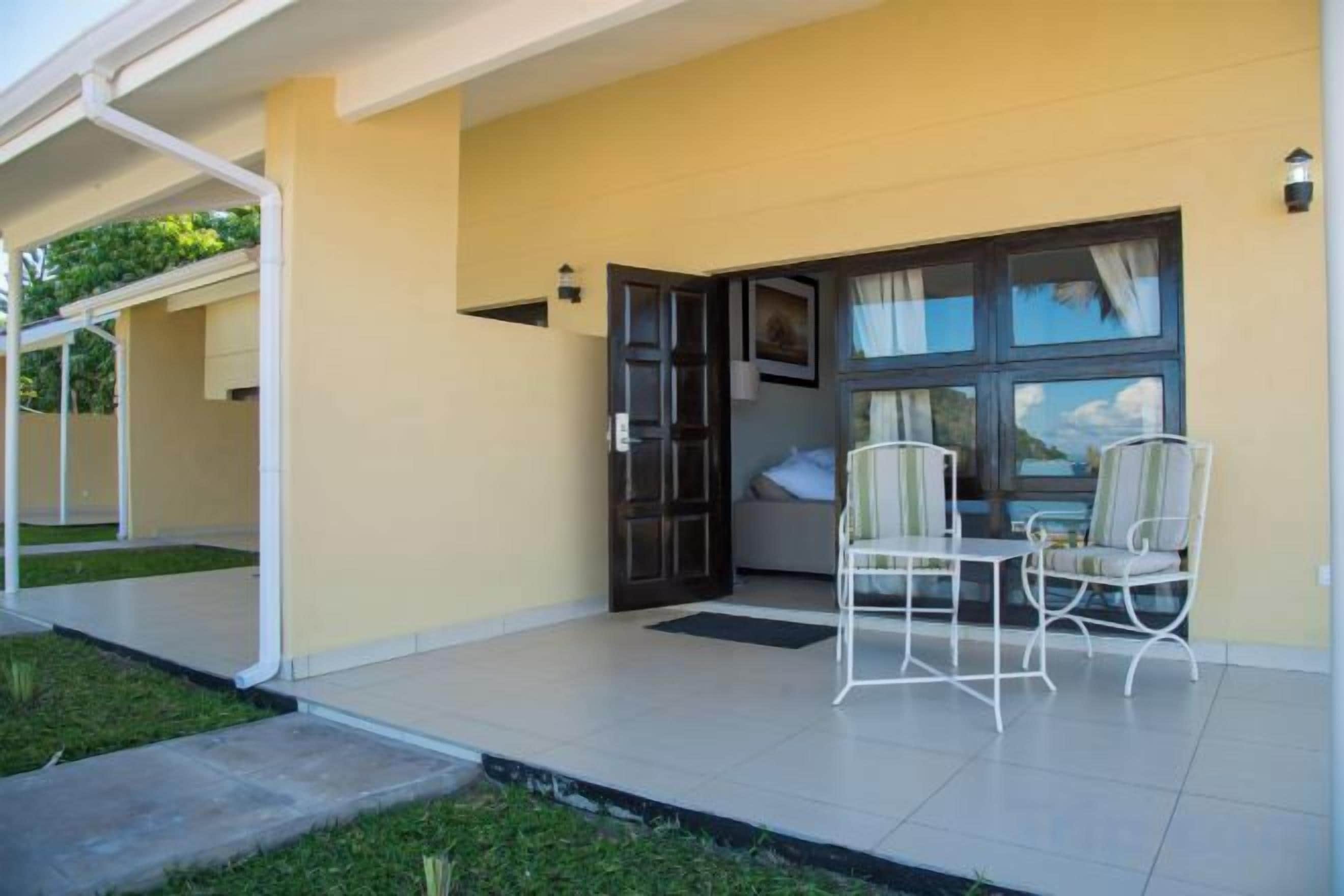 A building with a covered outdoor area, a door, and two chairs.