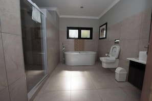 Un baño con cabina de ducha de vidrio, bañera y retrete.