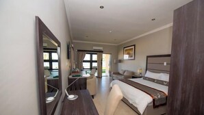A modern bedroom with a large bed, a desk, and a chair. There is a window with curtains and a painting on the wall.