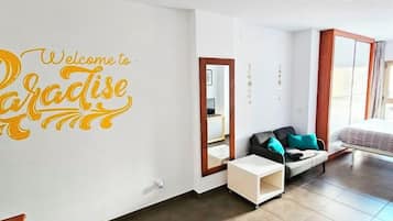 Een moderne woonkamer met een bank, een kleine tafel en een spiegel. Een grote wanddecoratie met de tekst