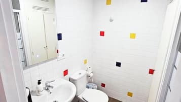 Een badkamer met witte tegels, een wastafel, toilet en spiegel.
