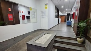 A modern lobby with a central seating area, a staircase, and informational posters on the walls. - Lala Loft, Las Canteras (Las Palmas)