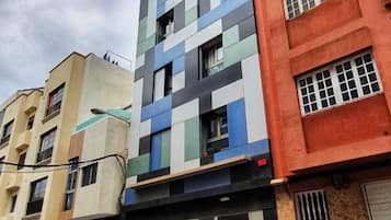 Een meerlaags gebouw met een moderne gevel, gekenmerkt door een combinatie van geometrische patronen en verschillende soorten ramen.