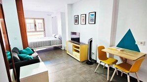 A compact living space with a bed, a desk, and a TV. - Lala Loft, Las Canteras (Las Palmas)