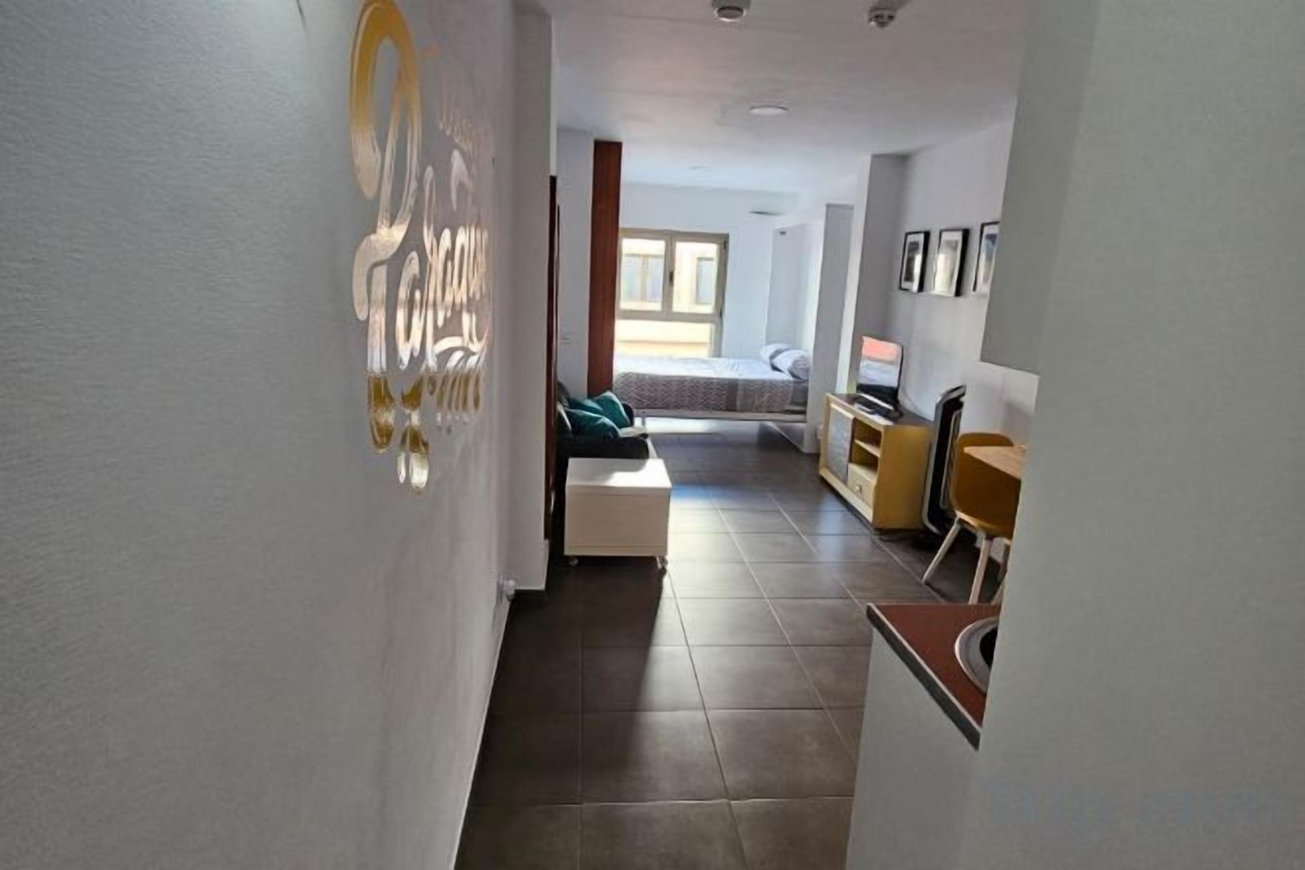 Un couloir menant à une chambre à coucher équipée d’un lit, d’un bureau et d’une chaise.