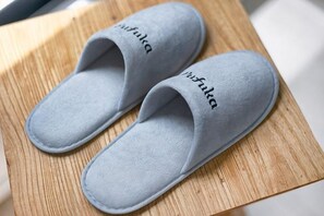 A pair of gray slippers with the word 'whitla' on them, placed on a wooden surface. - Pufuka Wakakusa (Tokyo)