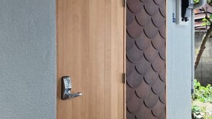 Una puerta de madera con cerradura electrónica y un panel decorativo con un diseño que recuerda a escamas.
