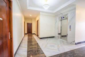 A hallway with marble flooring, a wooden door, and a marble wall. - Angkor Golden Guest House (Siem Reap)