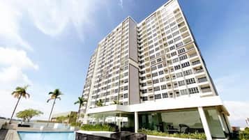 A high-rise building with multiple balconies, a swimming pool, and outdoor seating.