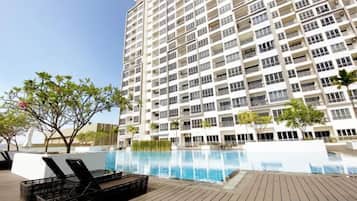 A high-rise building with a swimming pool and lounge chairs.