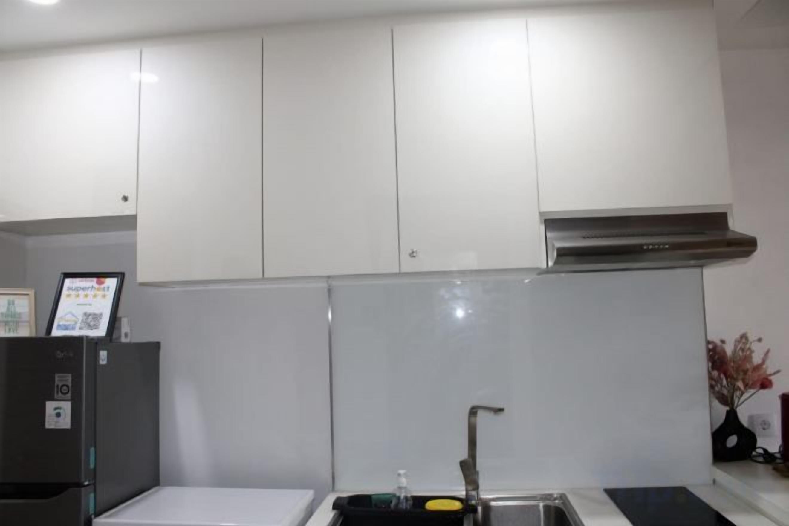 A kitchen with white cabinets, a stainless steel range hood, and a black countertop.