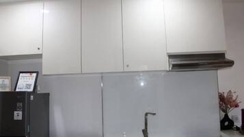 A kitchen with white cabinets, a stainless steel range hood, and a black countertop.