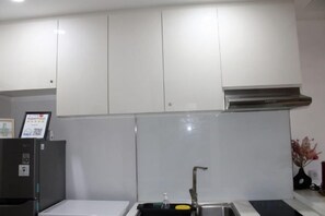 A kitchen with white cabinets, a stainless steel range hood, and a black countertop.