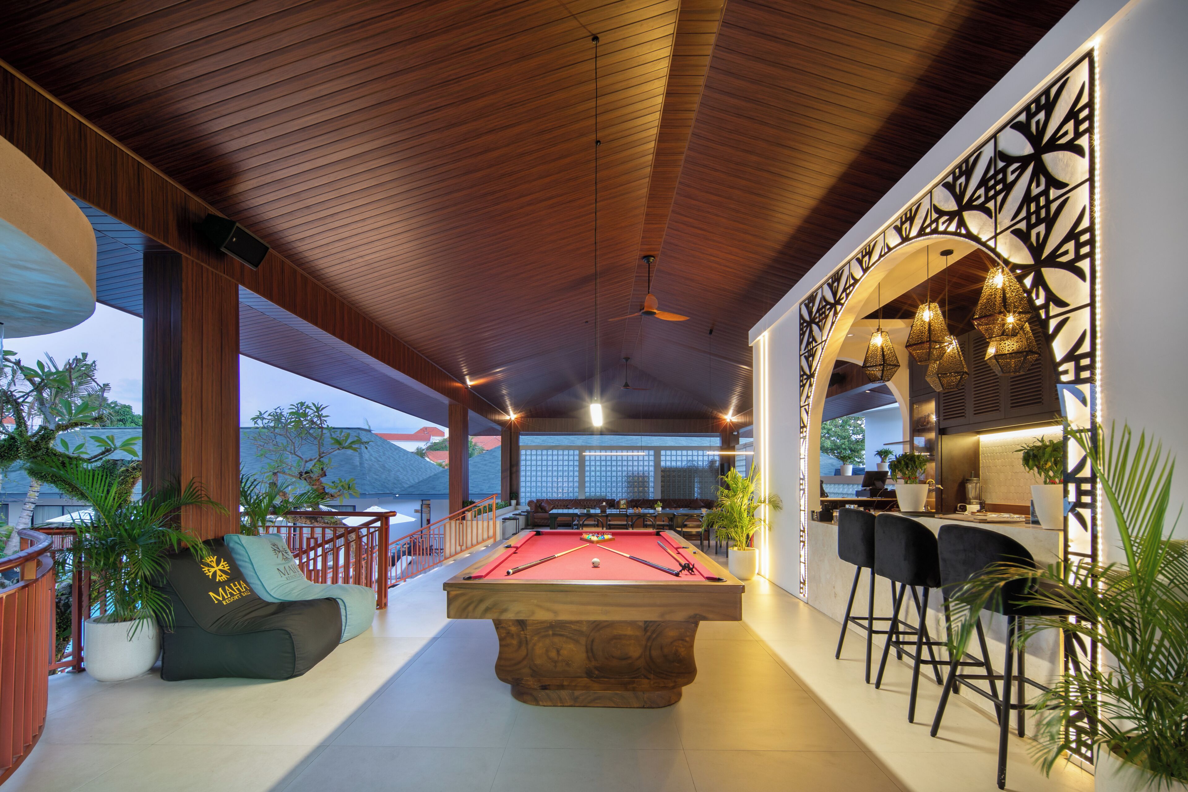 A pool table with surrounding seating, a bar area, and a view of the outdoors.