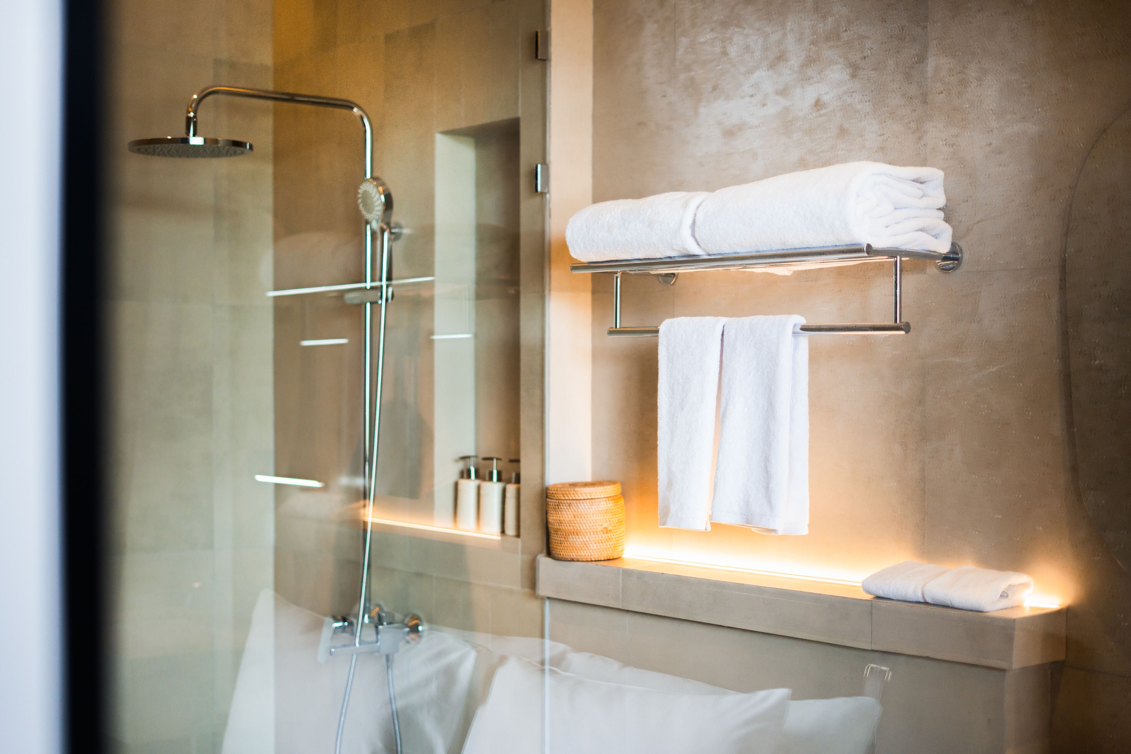 A modern bathroom with a glass-enclosed shower, a vanity with a towel rack, and a mirror.