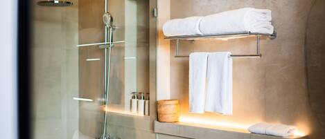 A modern bathroom with a glass-enclosed shower, a vanity with a towel rack, and a mirror.