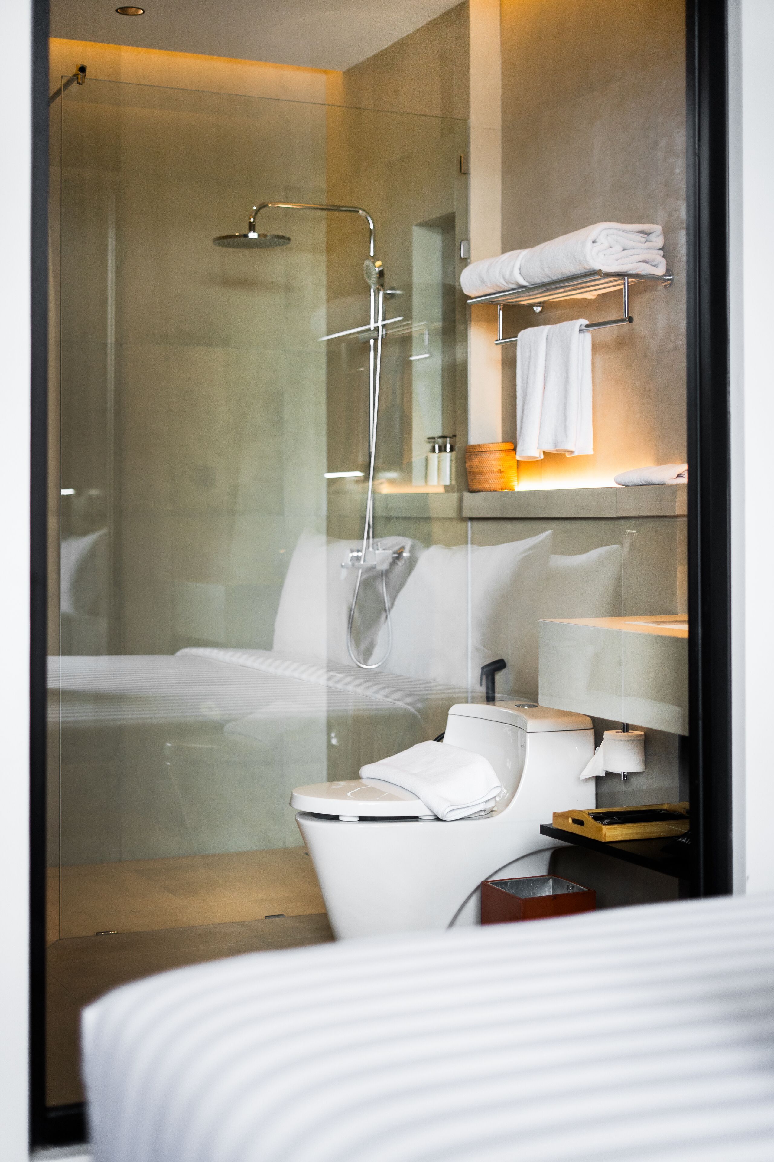 A modern bathroom with a glass shower enclosure, a white toilet, and a neatly arranged towel rack.