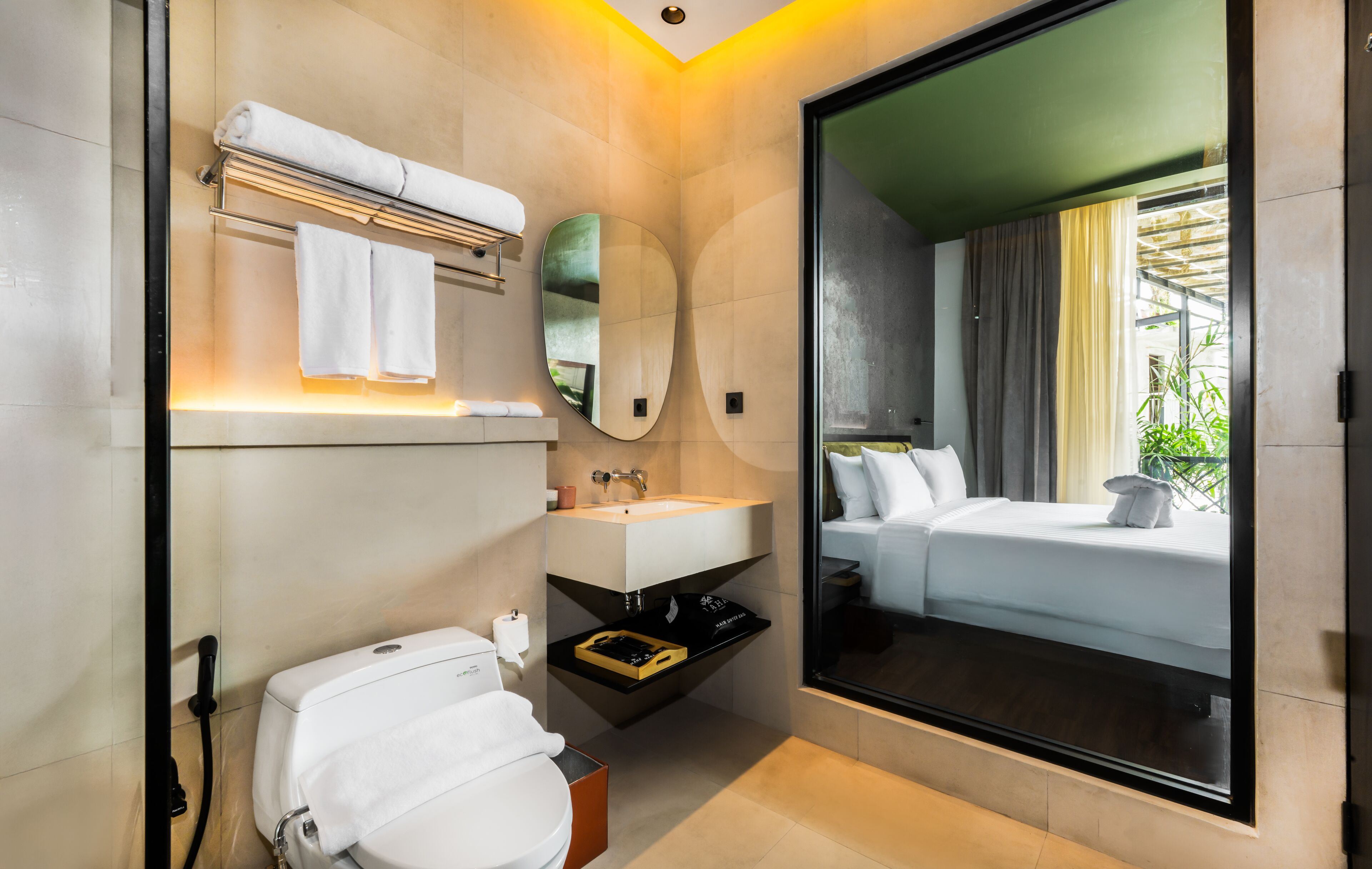 A modern bathroom with a toilet, sink, and a large mirror.