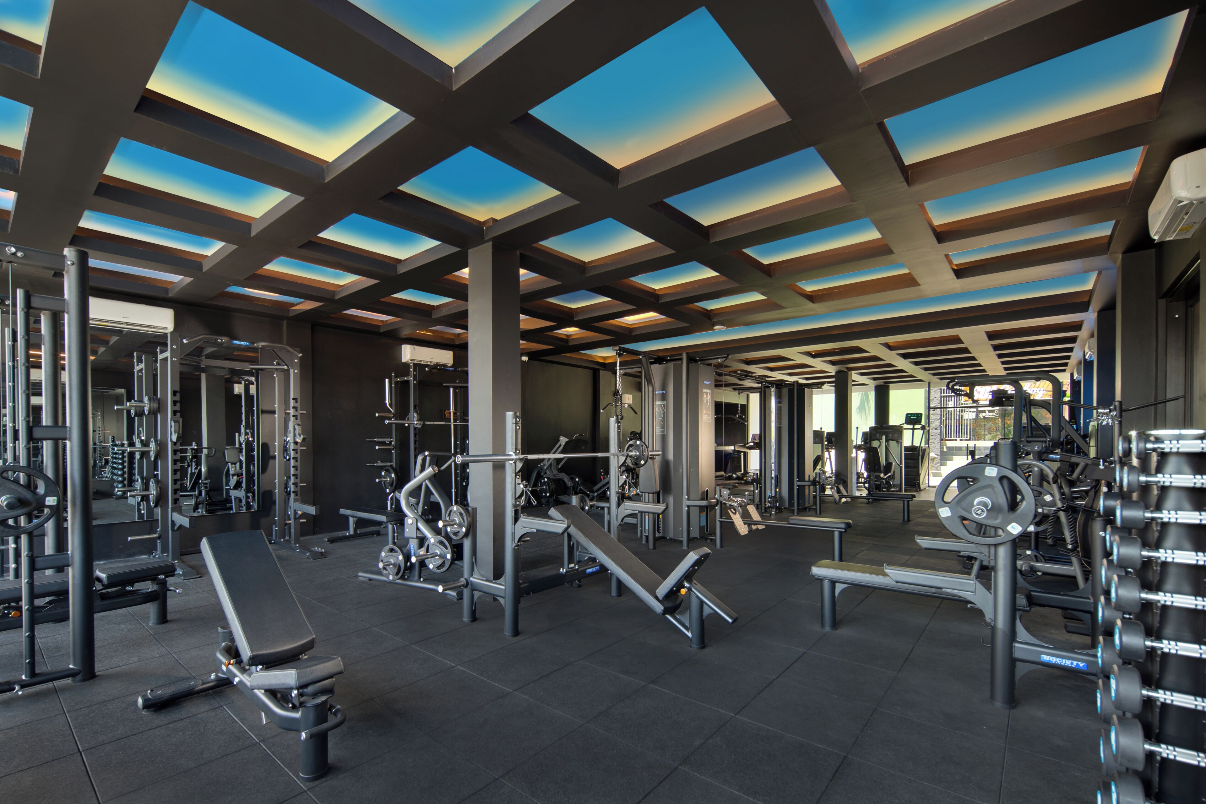 A gym with various exercise equipment, a bench, and a mirrored wall.