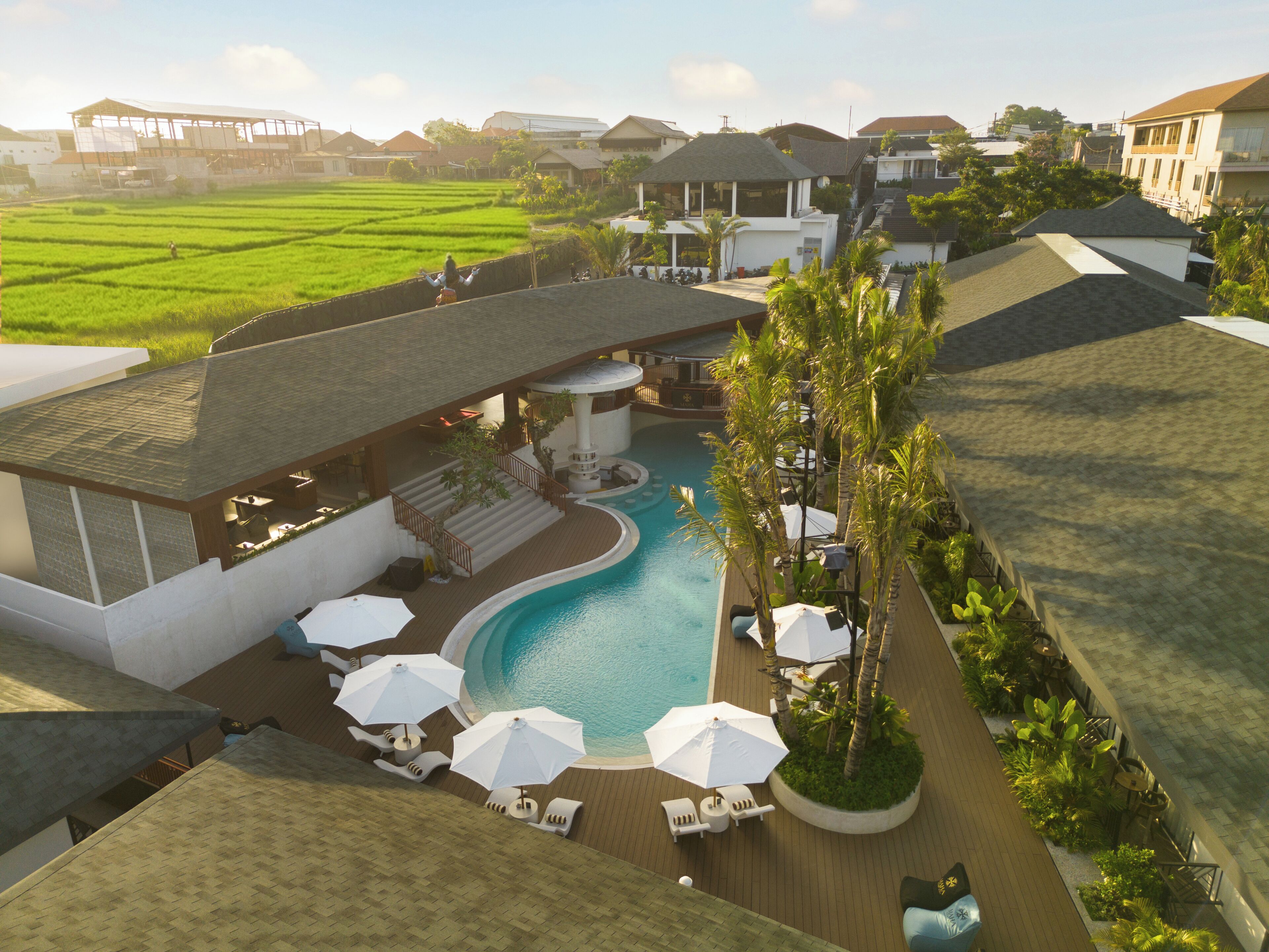 A resort with a swimming pool, lounge chairs, and a view of the surrounding landscape.