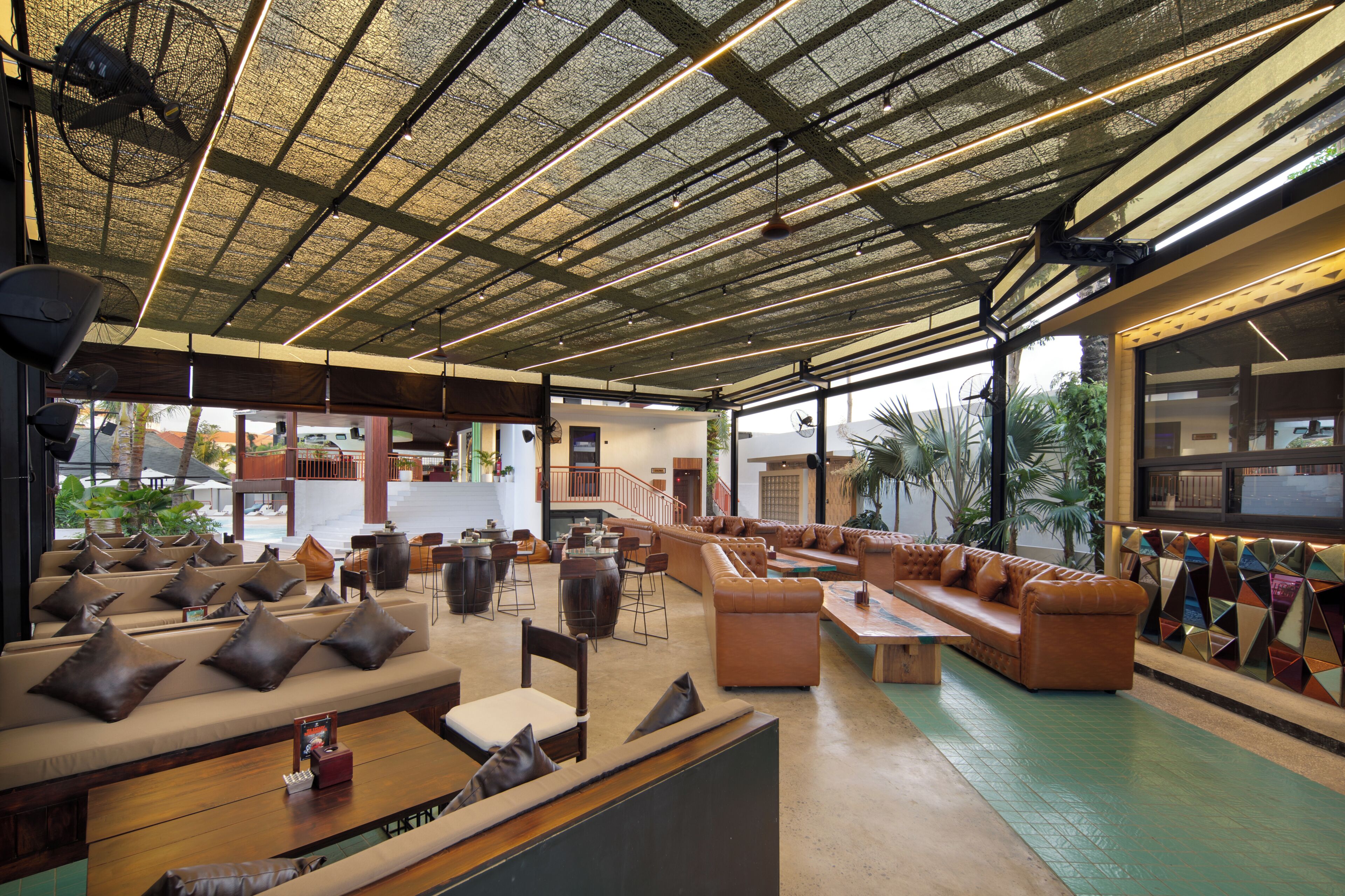 A spacious lounge area with multiple seating options, including sofas and chairs, and a visible staircase leading to an upper level.
