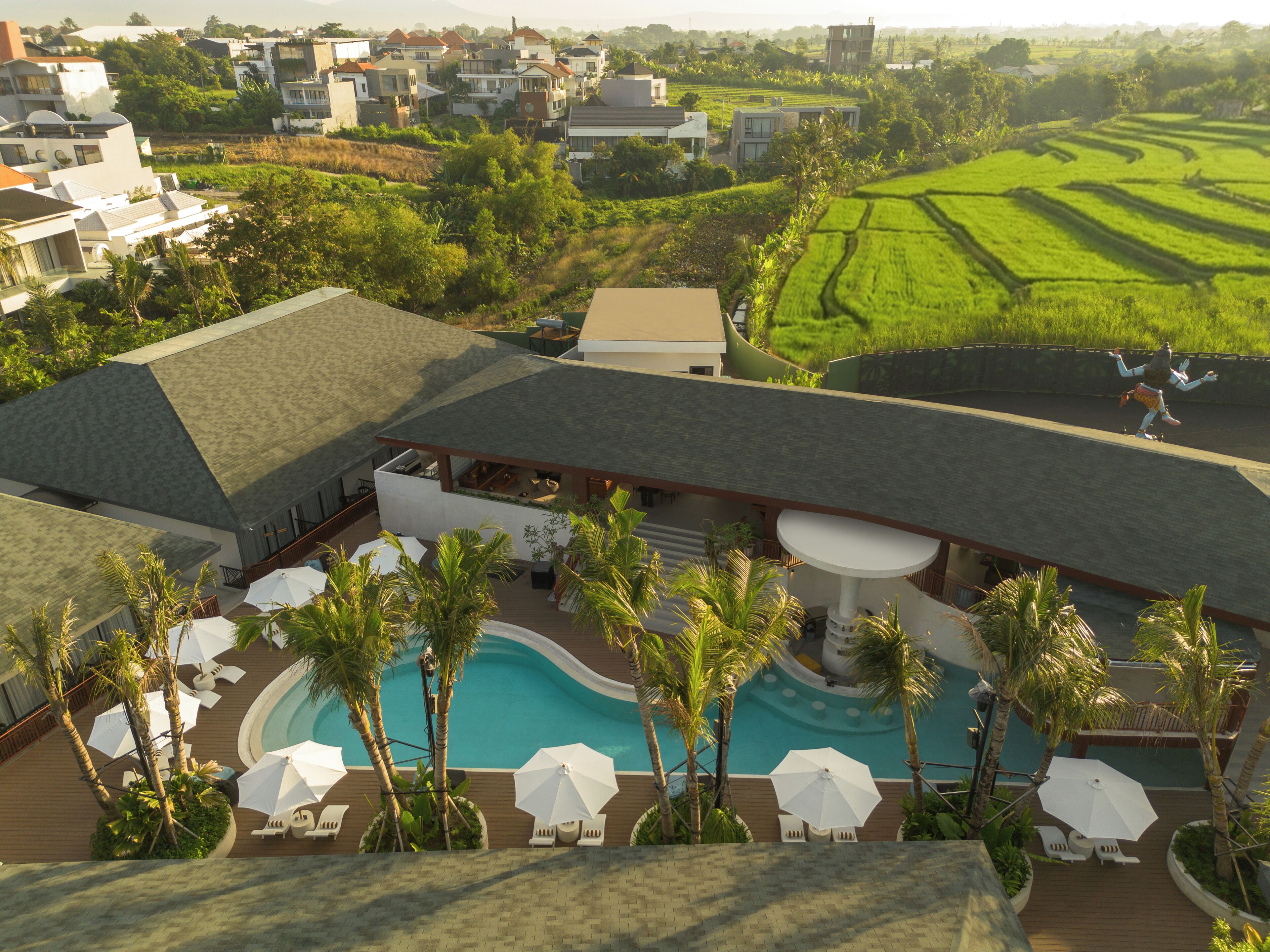 A resort with a swimming pool, lounge chairs, and palm trees.