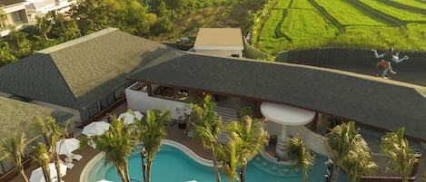 A resort with a swimming pool, lounge chairs, and palm trees.
