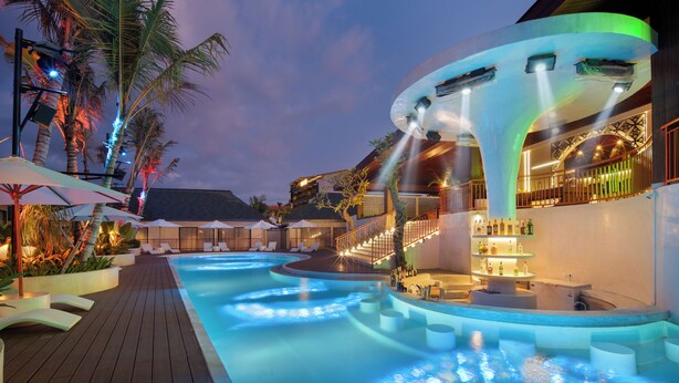 A pool area with lounge chairs, a bar, and a staircase leading to an upper level. - Maha Resort Bali (Canggu)