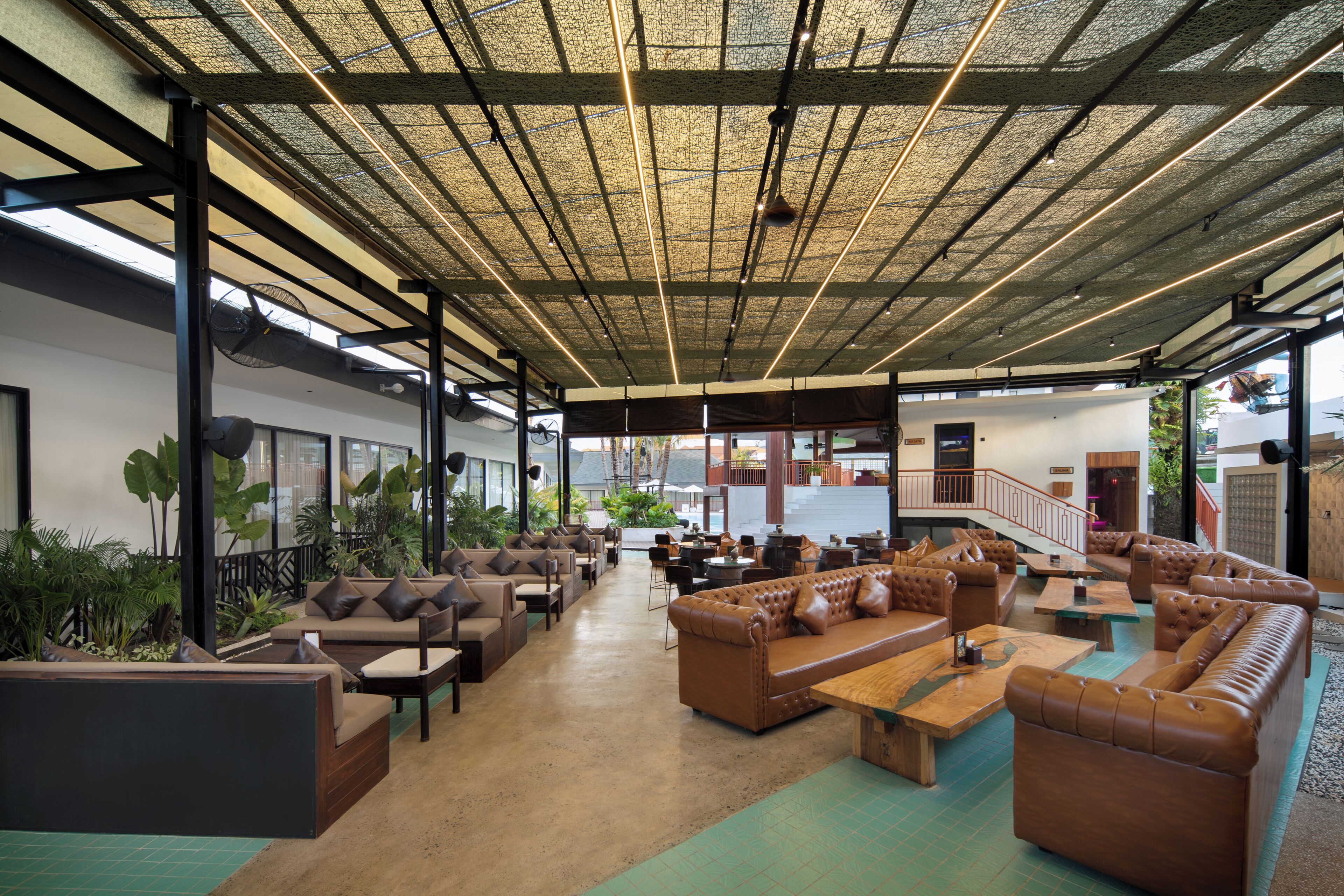 A spacious indoor area with multiple seating arrangements, a high ceiling with a grid pattern, and large windows allowing natural light.