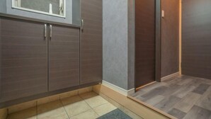 Un baño moderno con armarios de madera oscura, piso de baldosas y un ventanal pequeño.