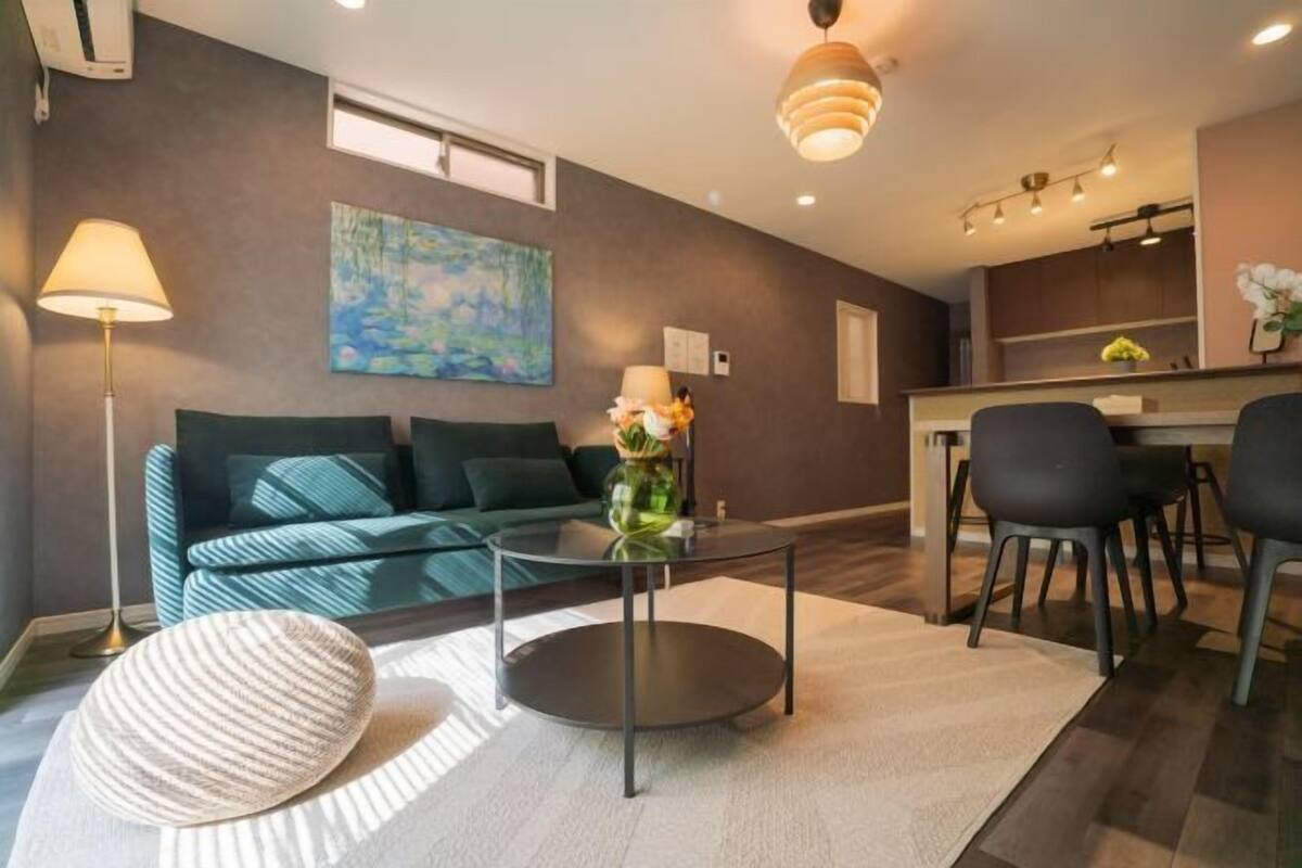 Een moderne woonkamer met een bank, een ronde glazen salontafel, een lamp en een schilderij aan de muur.