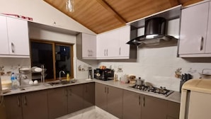 Une cuisine moderne dotée de plans de travail en marbre, d’appareils électroménagers en acier inoxydable et de poutres en bois au plafond.