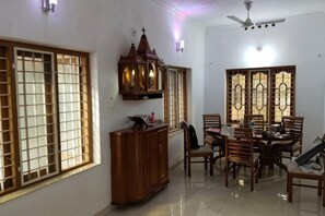 A dining area with a wooden table and chairs, a cabinet, and a ceiling fan. - Full AC 4bhk townhouse, 10 mins from airport (Angamali)