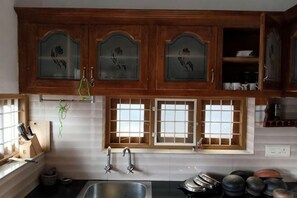 A kitchen with wooden cabinets, a sink, and a window with a view. - Full AC 4bhk townhouse, 10 mins from airport (Angamali)